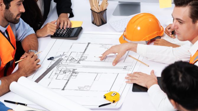 Engineers discussing blueprints at a meeting.